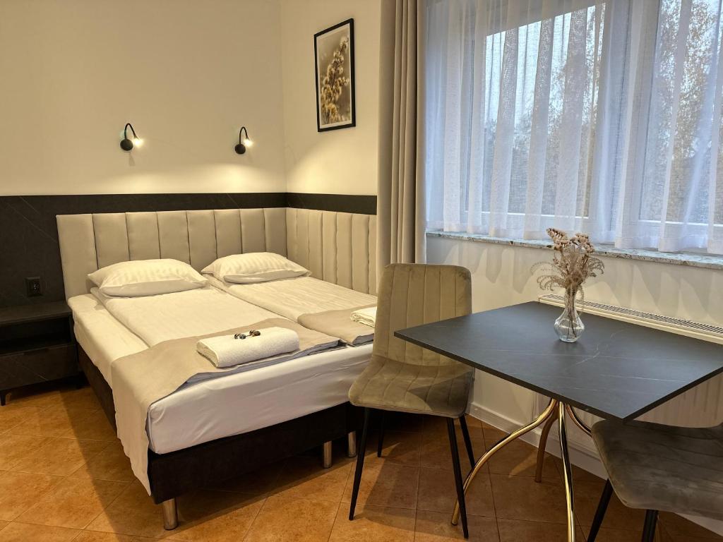 a small bedroom with a bed and a table at Pensjonat nad Jeziorem in Powidz