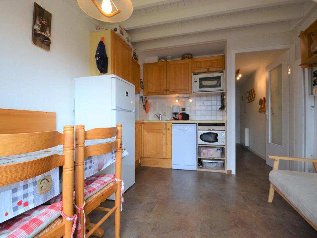 Elle comprend une petite cuisine équipée d'un réfrigérateur blanc et de placards en bois. dans l'établissement Duplex cosy au pied des pistes, 5 pers, parking couvert - FR-1-505-152, à Cohennoz