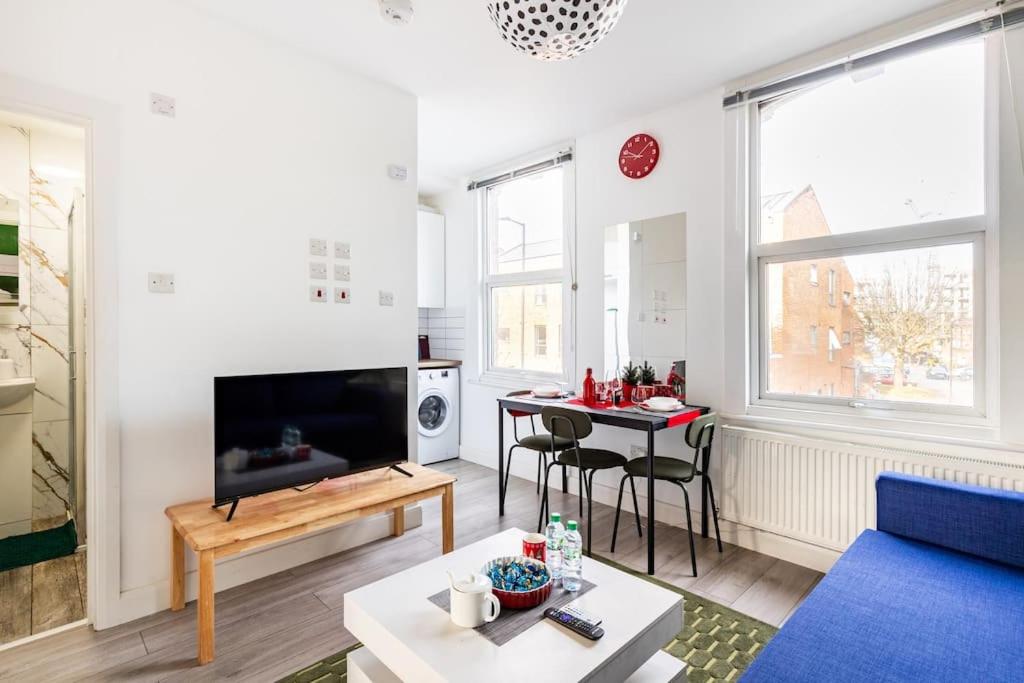 a living room with a blue couch and a table at Parkside Stay North London - Victoria Line in London