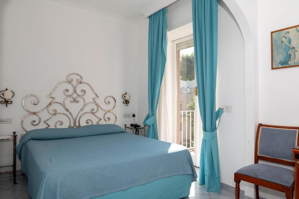 a bedroom with a blue bed and a window at Palatium Mari in Capri