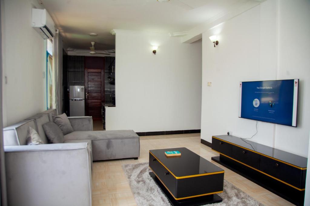 uma sala de estar com um sofá e uma televisão na parede em MIKOCHENI APARTMENT em Dar es Salaam