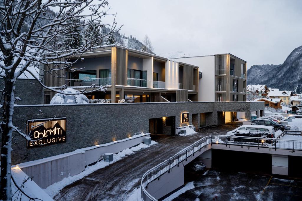 a building in the snow with a parking lot at DOLOMITI EXCLUSIVE YOUR MOUNTAIN SUITE in Pozza di Fassa