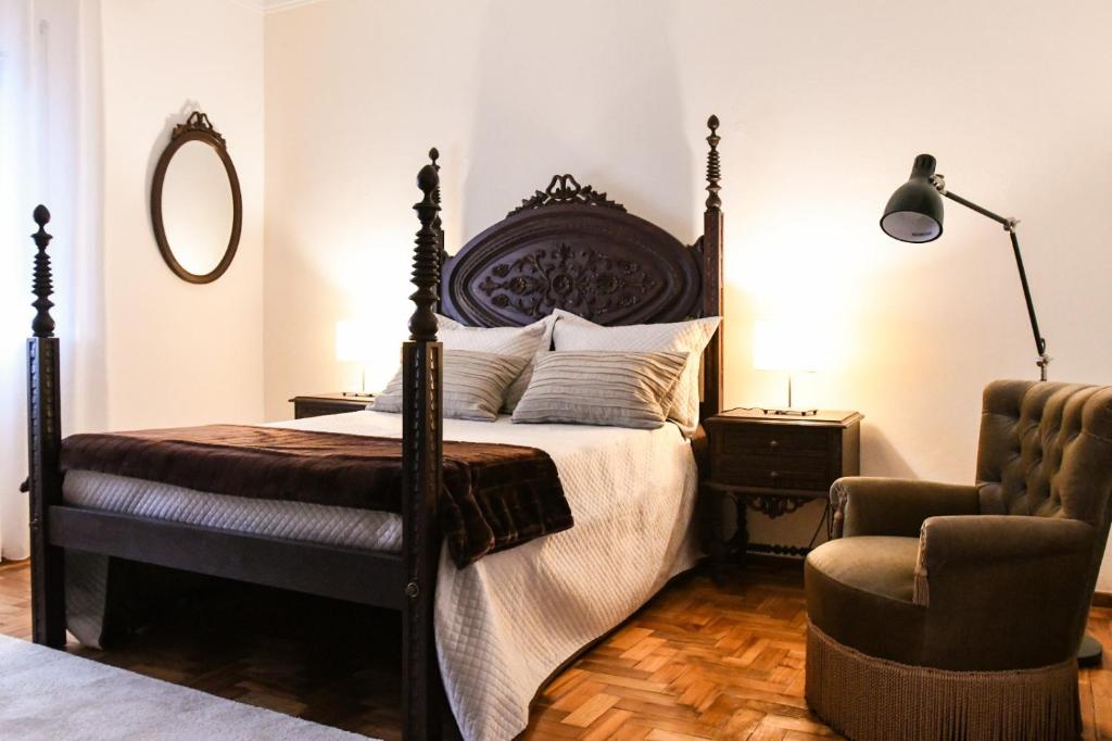 a bedroom with a large bed and a chair at Casa Raposo in Miranda do Corvo