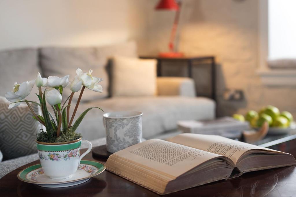 an open book on a table with a vase of flowers at The Bothy at Redheugh in Newcastleton
