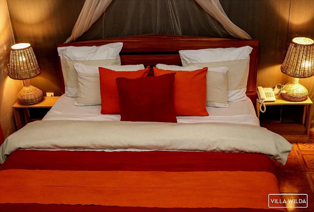 um quarto com uma cama grande e almofadas vermelhas e brancas em Villa Wilda em Bamako