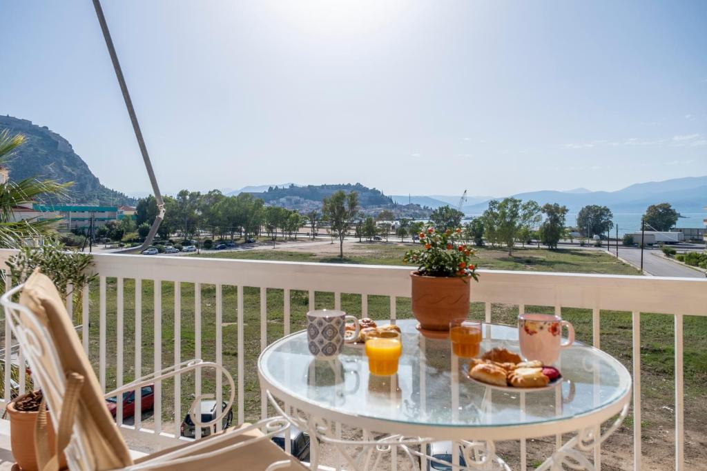 een glazen tafel met eten en sinaasappelsap op een balkon bij Likno Apartment in Nafplio