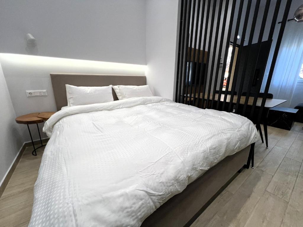 Un dormitorio con una gran cama blanca y una mesa en B1 Luxury Studio, en Alexandroupoli