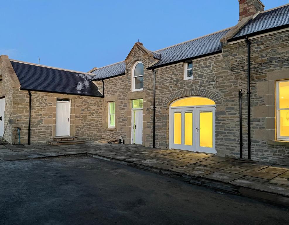 ein Backsteinhaus mit gelben Türen und einer Auffahrt in der Unterkunft Grainbank Mews in Kirkwall