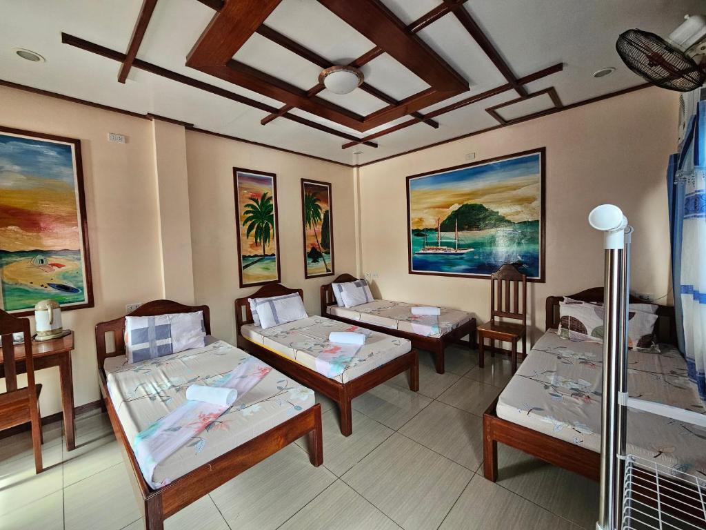 Habitación con 3 camas y pinturas en las paredes. en Ferranco Tourist Inn en San Vicente