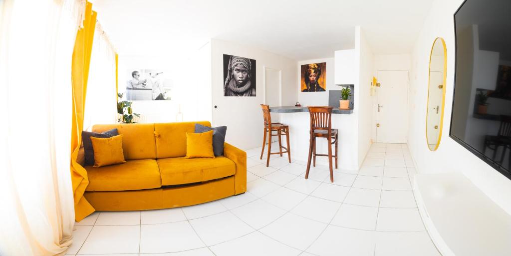 - un salon avec un canapé jaune et une table dans l'établissement Élégant Studio proche de Paris et Disneyland, à Villemomble