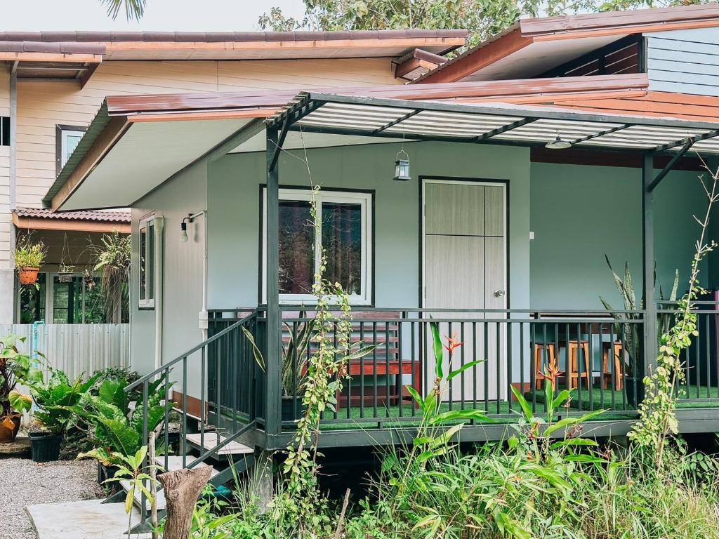 uma pequena casa verde com uma varanda em Baan Panmala Guesthouse - Ao Luek em Krabi