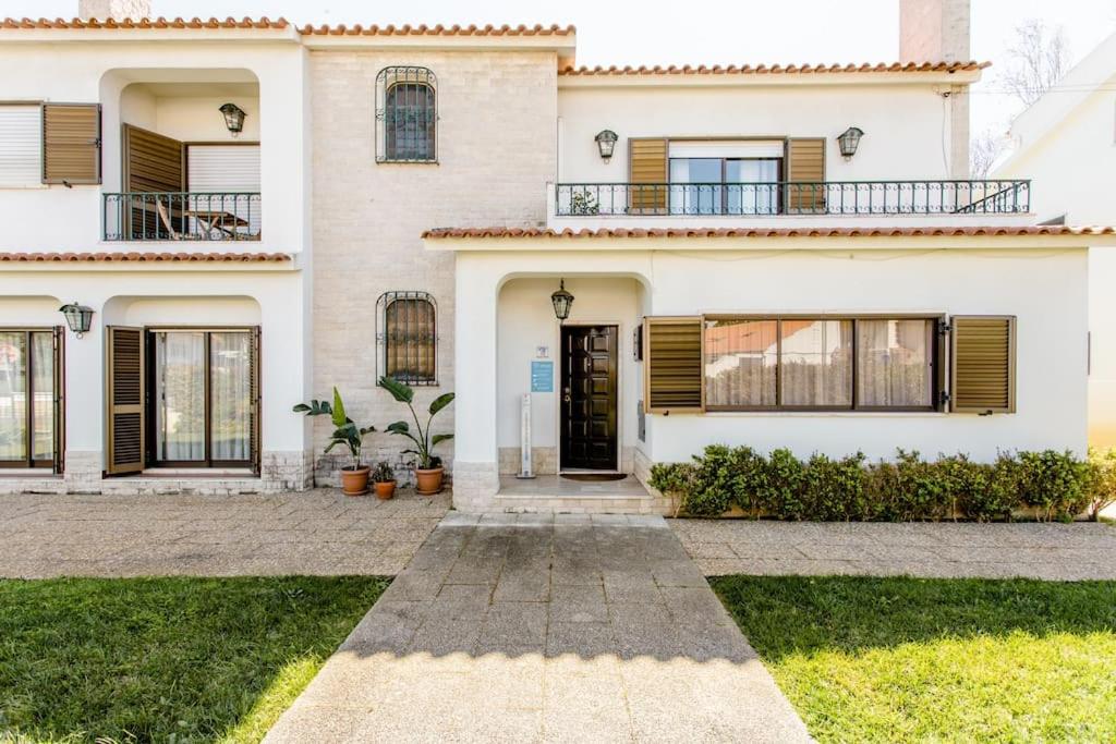 a white house with a door and a yard at Paradise Suites in Carcavelos