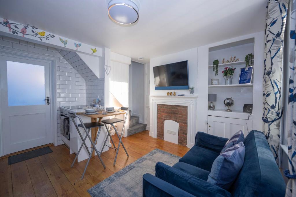 een woonkamer met een blauwe bank en een open haard bij The Little Marlowe - 1 Bed City Centre Cottage in Canterbury