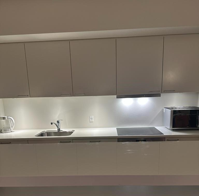 a kitchen with white cabinets and a sink and a microwave at Attraktiv lejlighed in Odense