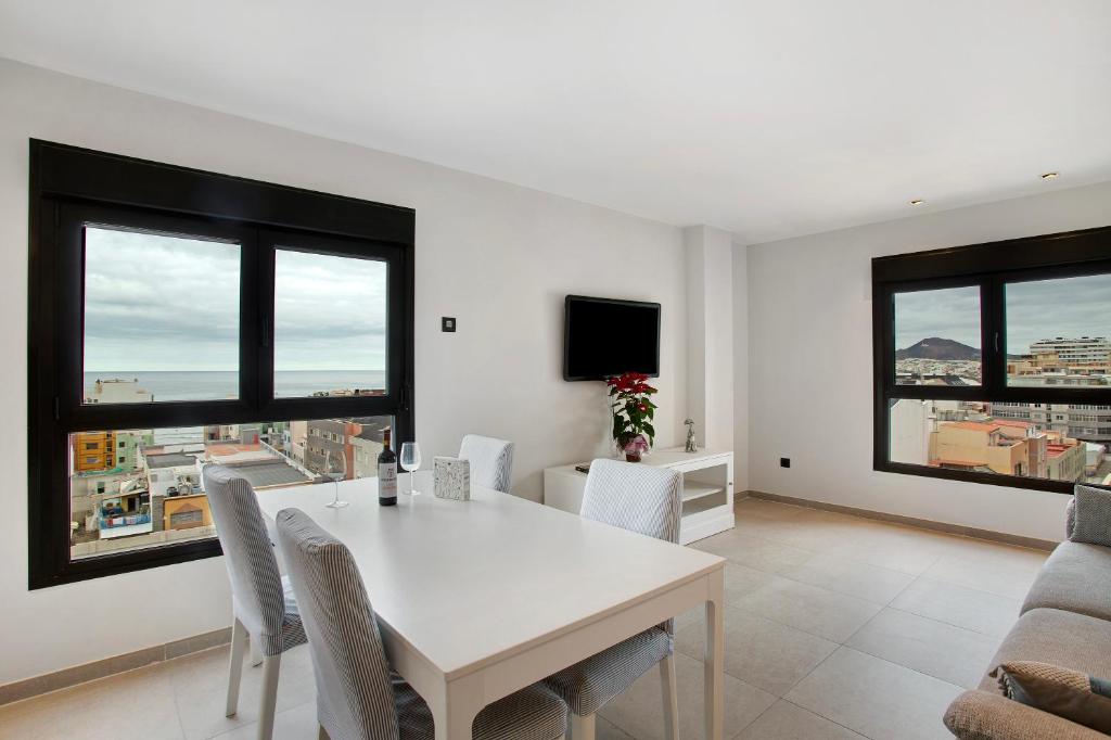 a dining room with a table and chairs and windows at Guanarteme Bureba 7 in Las Palmas de Gran Canaria