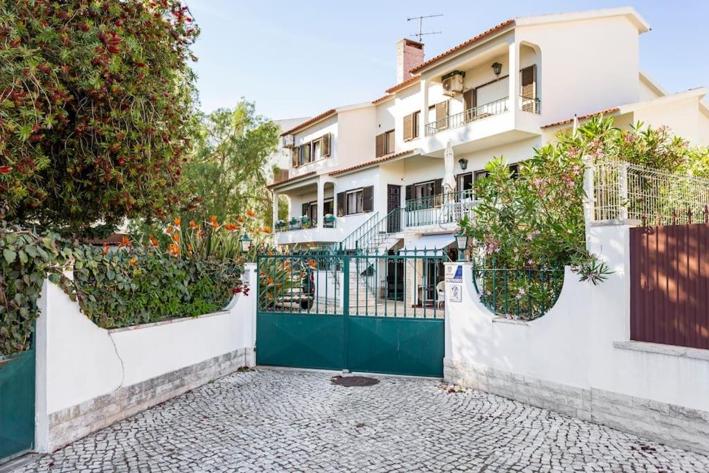 a house with a green gate and trees at Paradise Suites in Carcavelos