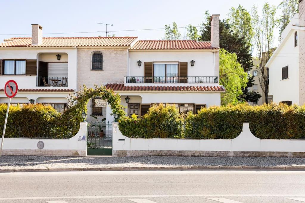 a white house with a gate in front of a street at Paradise Suites in Carcavelos