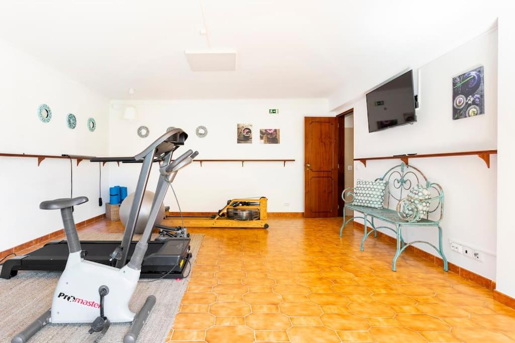 a room with a gym with a treadmill and a couch at Paradise Suites in Carcavelos