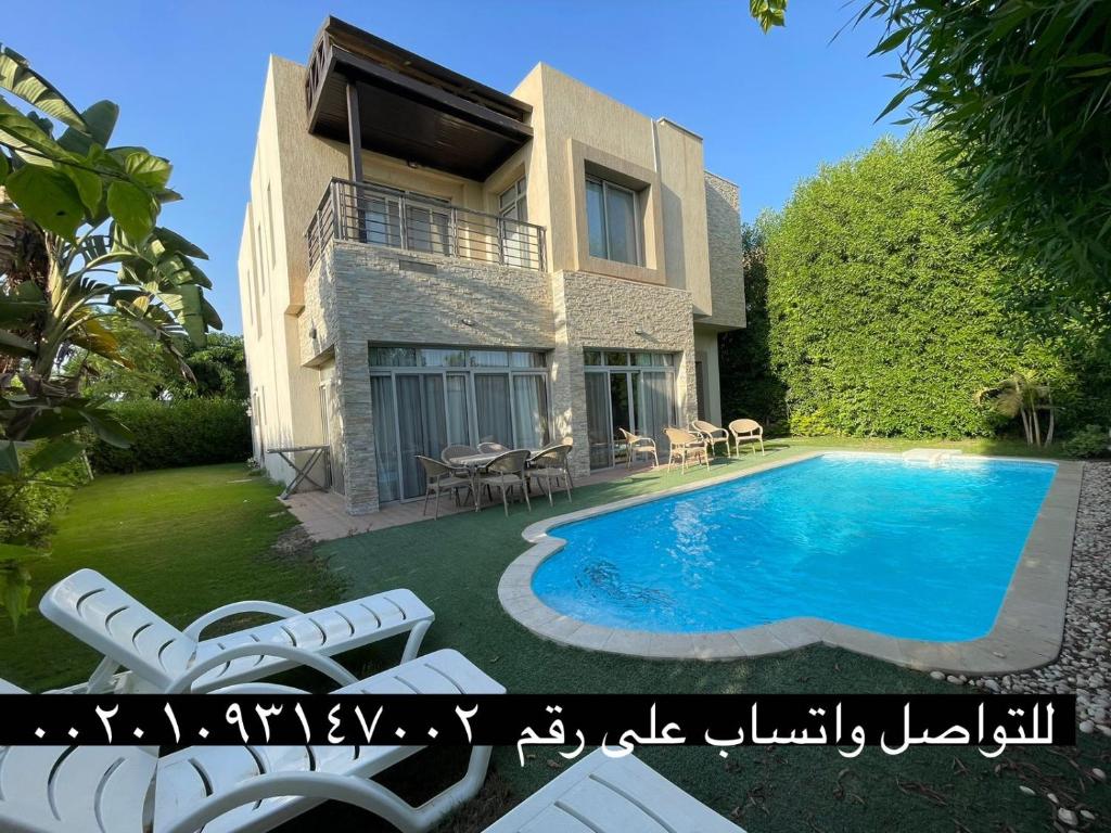 a villa with a swimming pool in front of a house at Villa paradise for rent in Elshikh zayed in Abū Rawwāsh