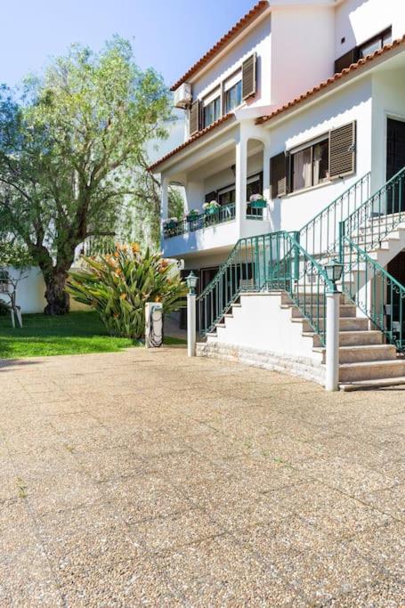 a white house with stairs and a balcony at Paradise Suites in Carcavelos