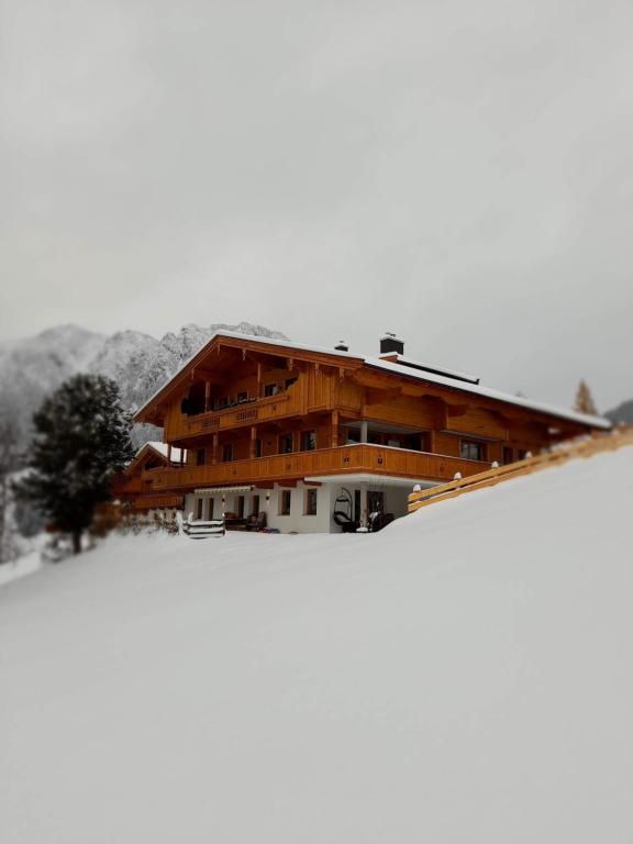 a large wooden house on top of a snow covered slope at Topp Rossmoos in Alpbach