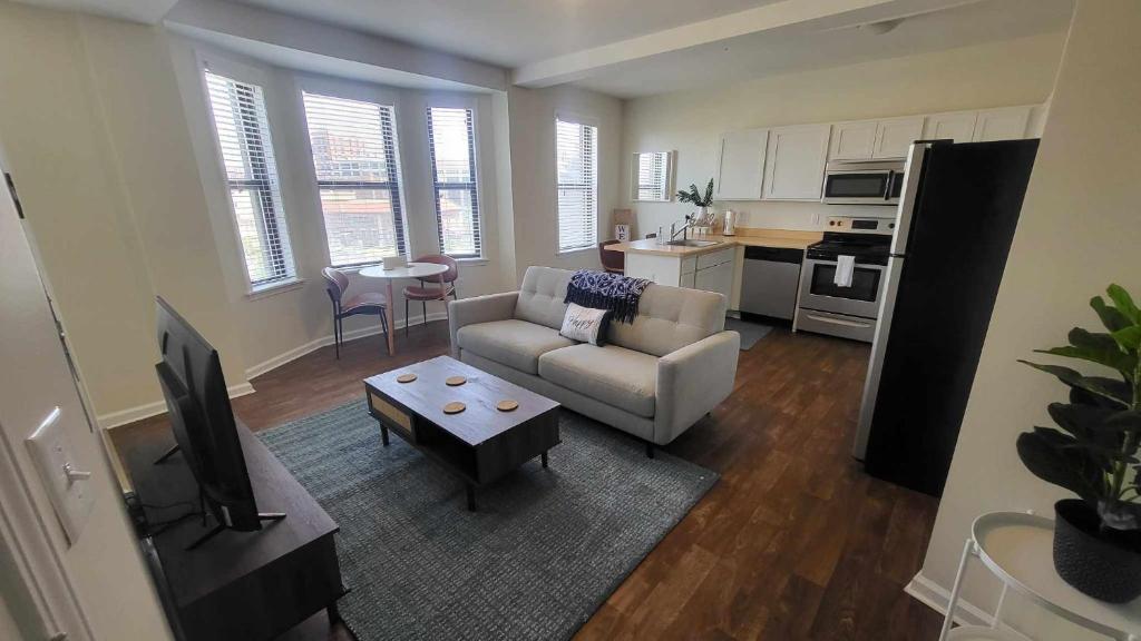 a living room with a couch and a tv and a kitchen at Amazing 1 BR Apt In City Center in Detroit