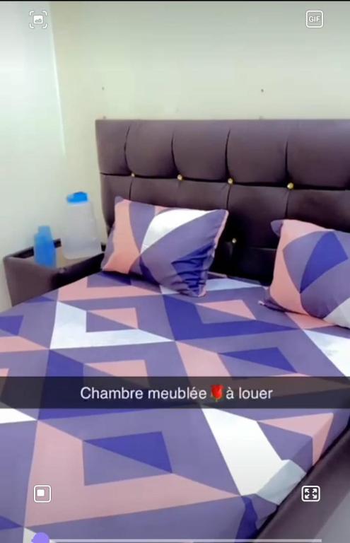 ダカールにあるCHAMBRE MEUBLEのカラフルな枕が付いたベッド1台が備わる客室です。