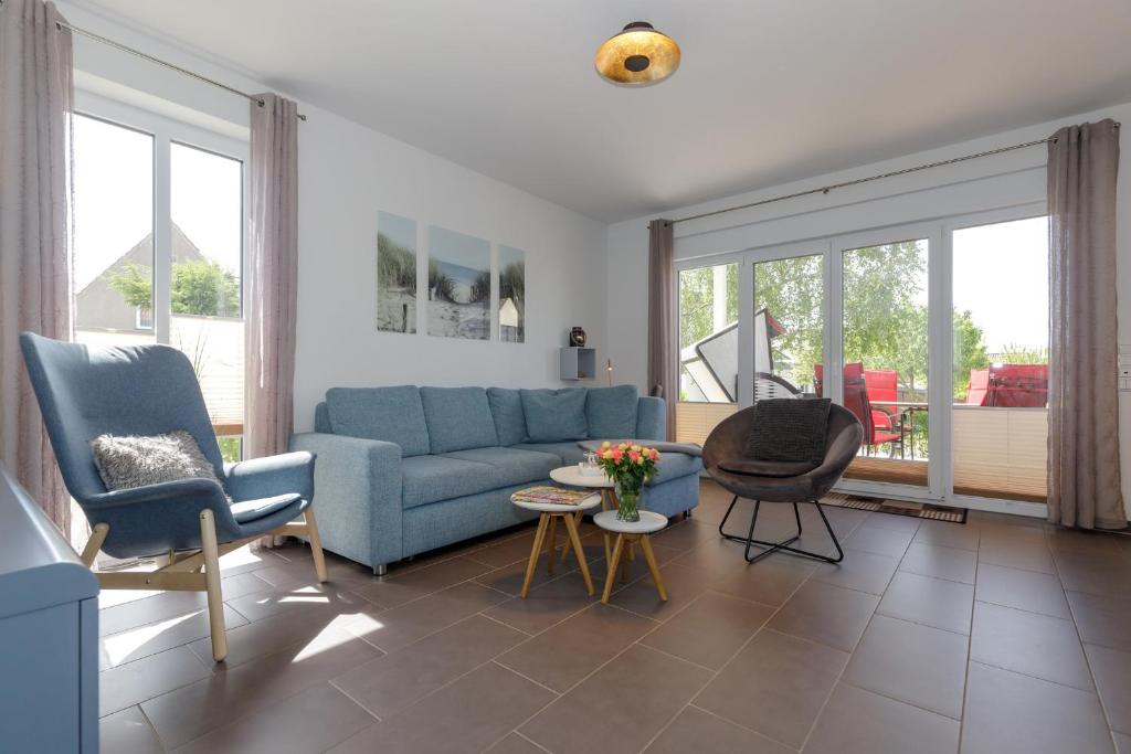 a living room with a blue couch and chairs at Haus Emilia Whg Baltic Dreams in Rerik