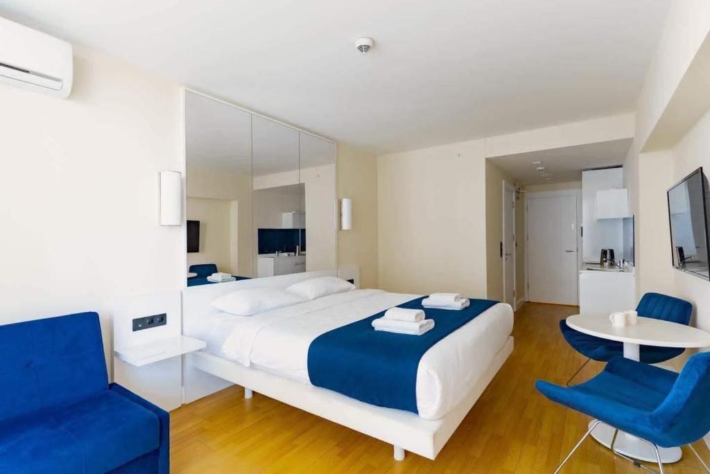 a bedroom with a large bed and two blue chairs at Orbi City Sea View in Batumi