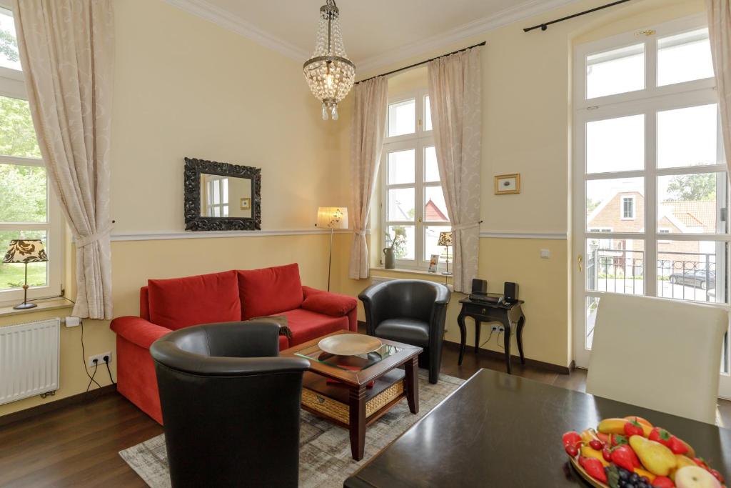 een woonkamer met een rode bank en een tafel bij Gutsschloss Rerik, "Belle Etage" in Rerik