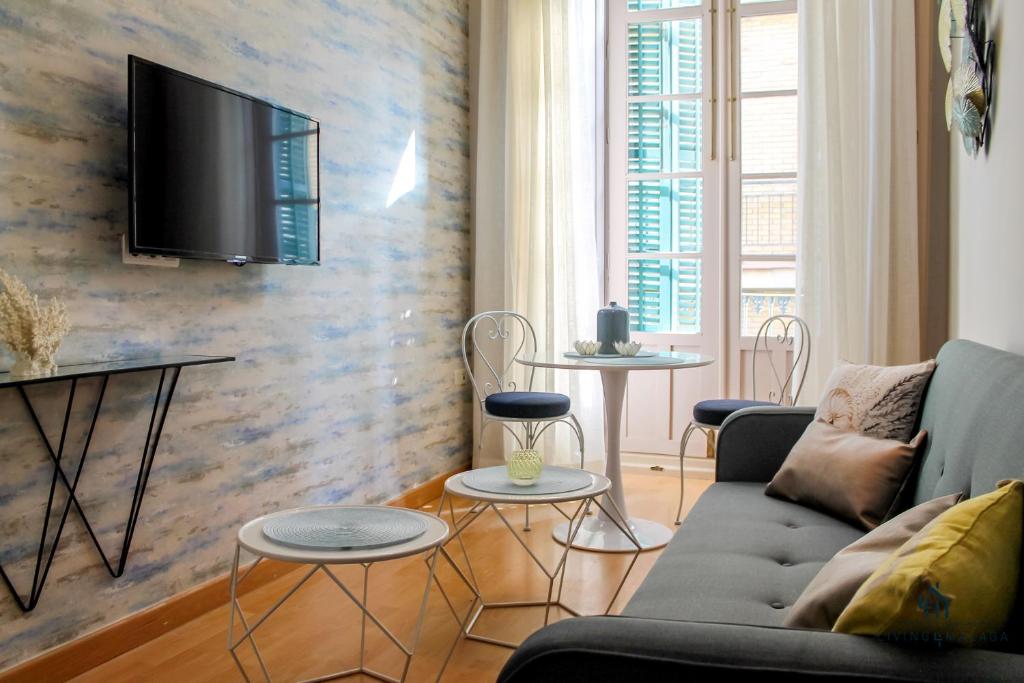 a living room with a couch and a tv on a wall at Living4malaga Spring Boutique in Málaga