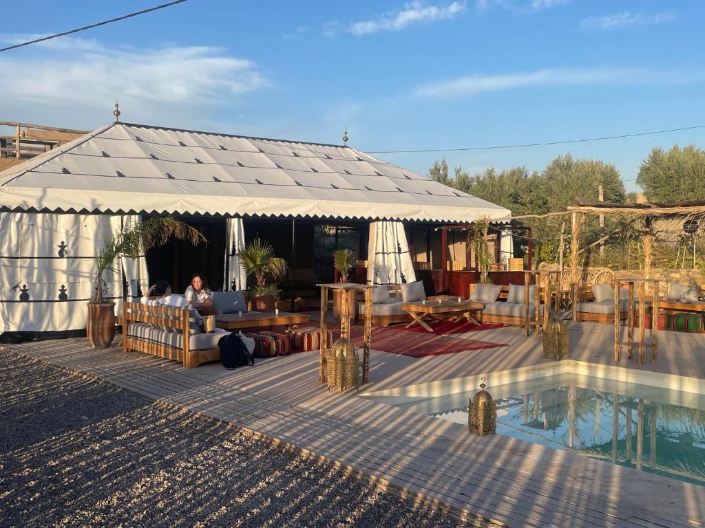 Agafay, La Ferme Nomade Bivouac في El Karia: خيمة مع طاولة وكراسي ومسبح