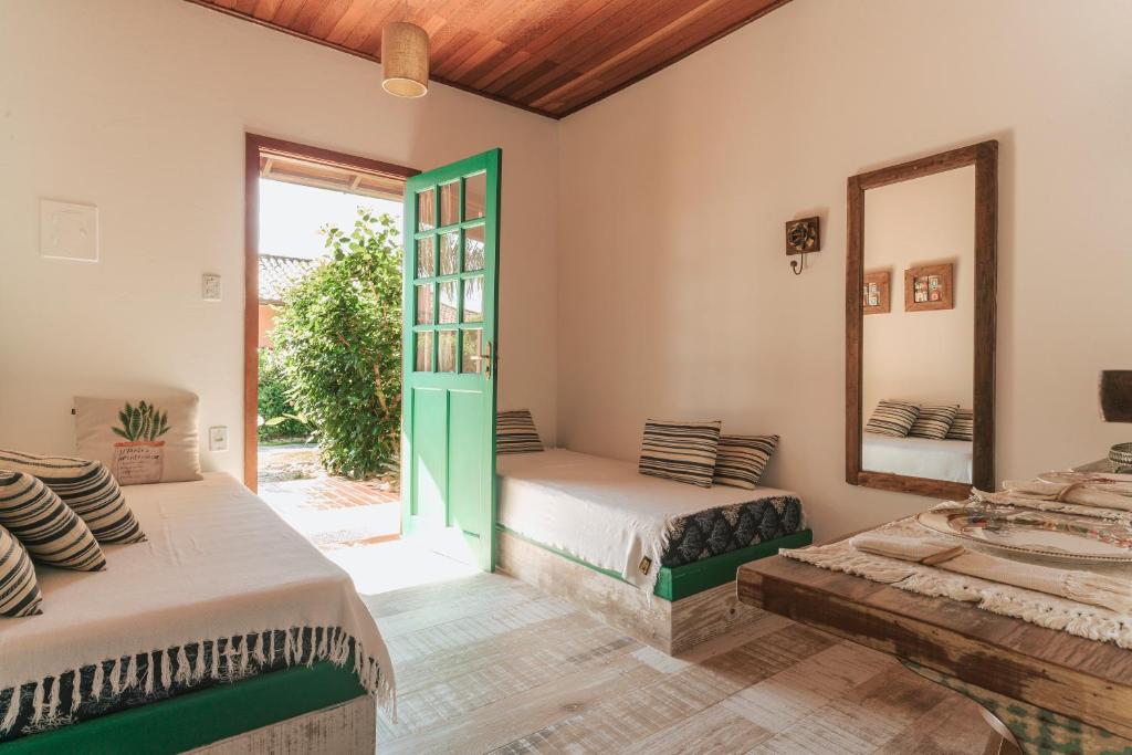 two beds in a room with a mirror and a window at Pousada Vila Campeche in Florianópolis