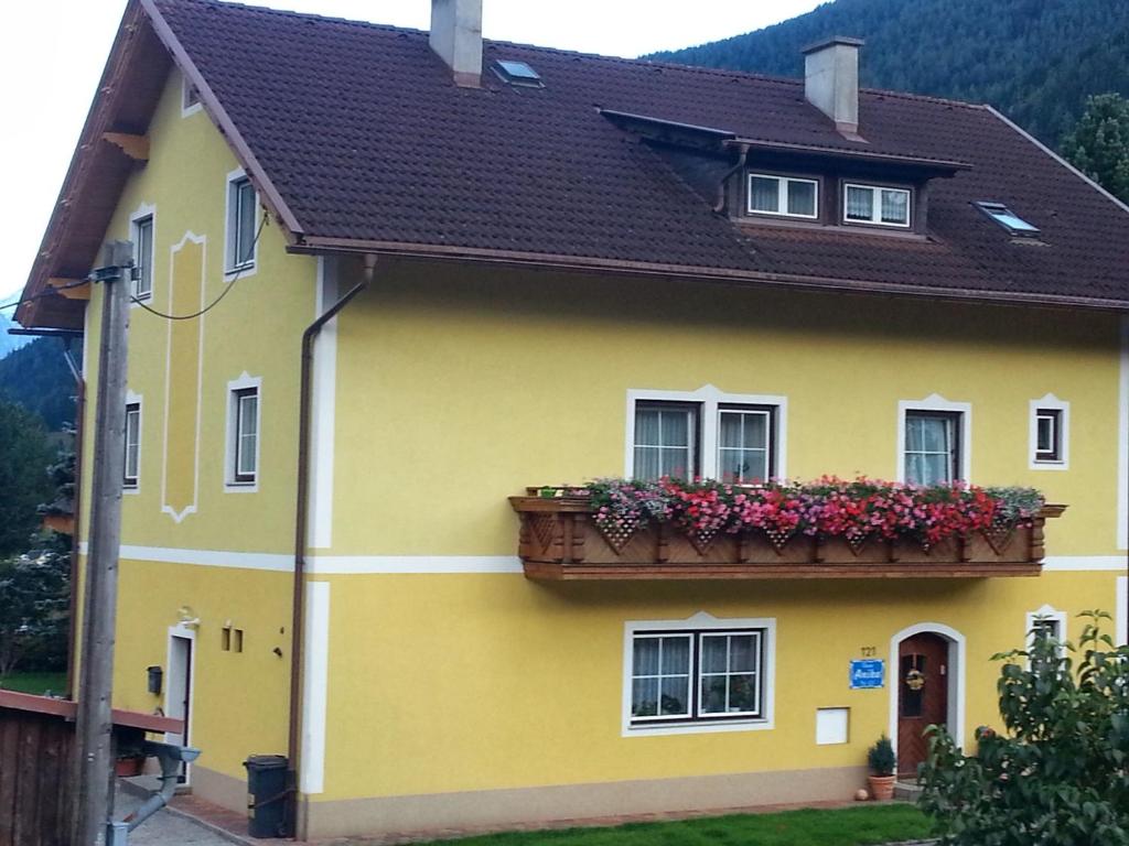 a yellow house with a balcony with flowers on it at Haus Anika Ferienwohnung in Mallnitz