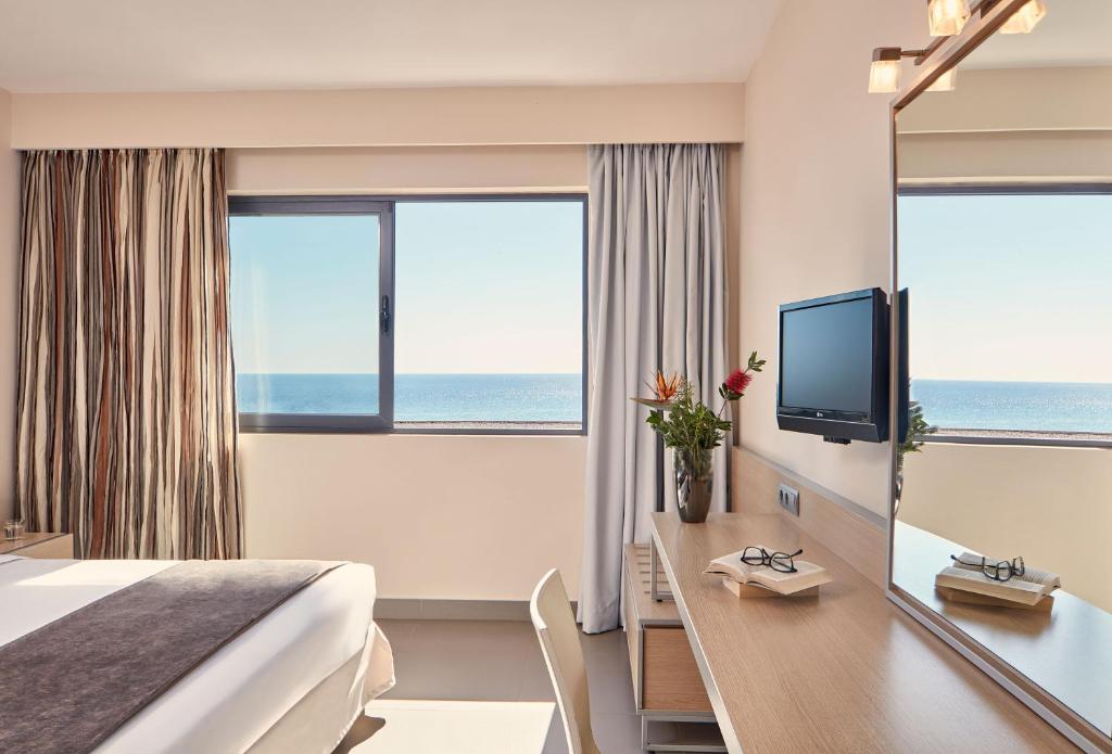 Pokój hotelowy z łóżkiem i biurkiem z telewizorem w obiekcie Atlantica Mikri Poli Crete w mieście Makry Gialos