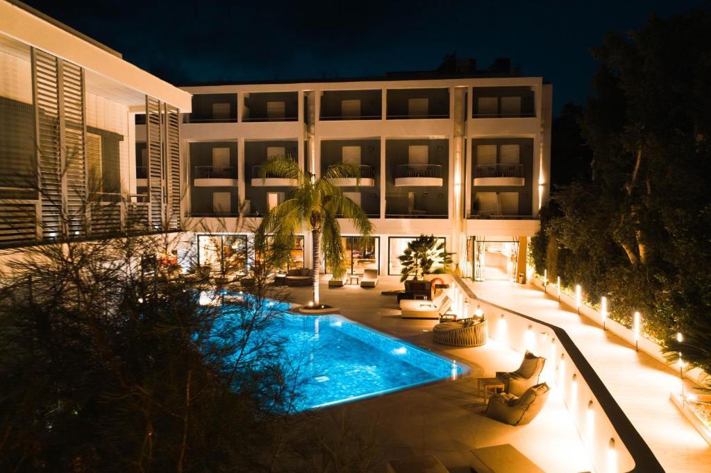 a large building with a swimming pool at night at Flisvos Royal in Tolo