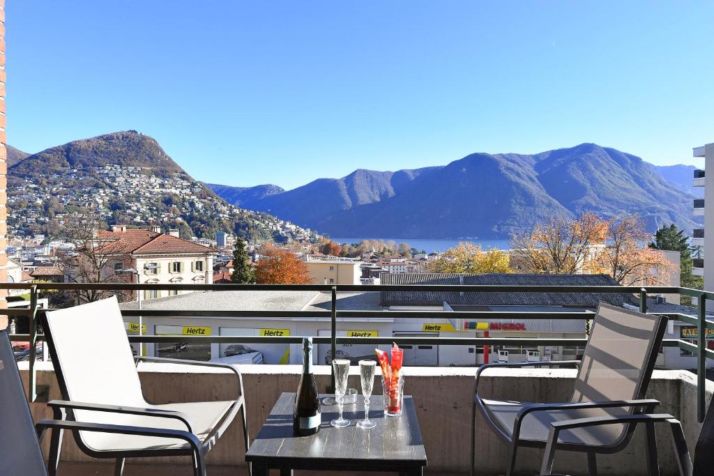 uma mesa e cadeiras numa varanda com montanhas em Santiago Home em Lugano
