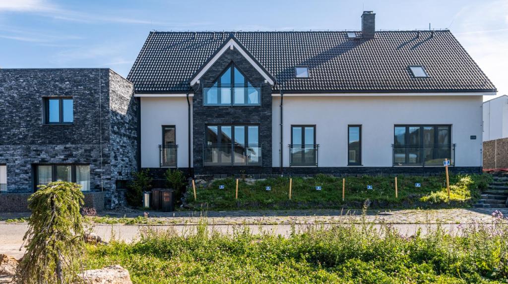 ein großes weißes Haus mit schwarzem Dach in der Unterkunft Family Apartments Klínovec in Loučná pod Klínovcem