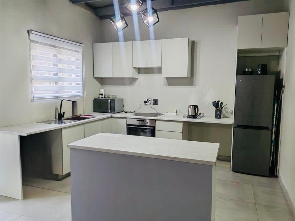 a kitchen with white cabinets and a black refrigerator at Tranquil Escapes Bramley in Johannesburg