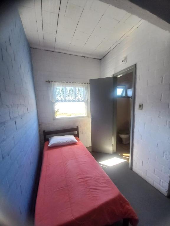 Un pequeño dormitorio con una cama roja en una habitación en Brisa do Mar Hotel en Arroio do Sal
