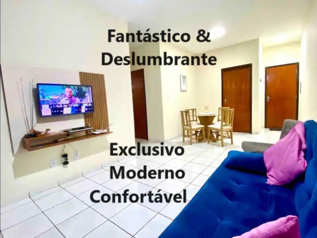 a living room with a blue couch and a tv at Apto charmoso e espaçoso no Centro, térreo com 2 Quartos ArCond WiFi HomeOfice Cozinha e Garagem in Dourados