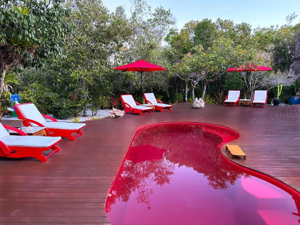 a pool with chairs and umbrellas on a deck at Cristal da Mata - Casa exclusiva e privativa in Caraíva