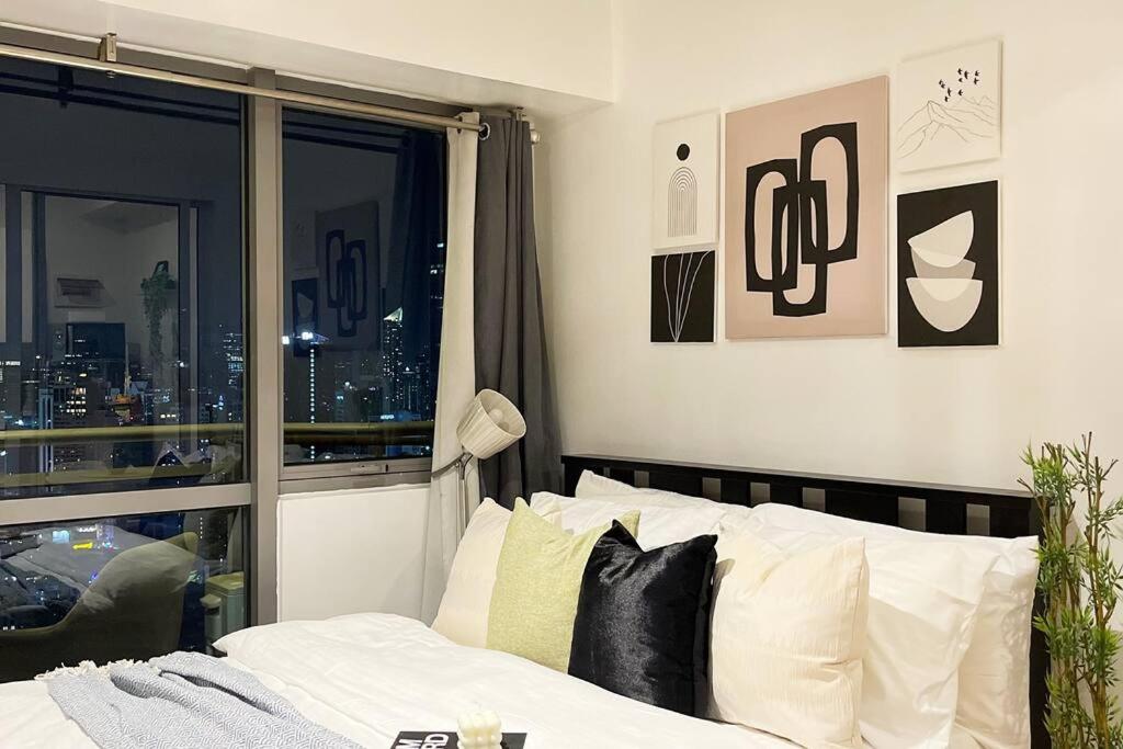 a bedroom with a bed with a view of a city at The Serene Escape Rockwell Makati City View 1BR in Manila