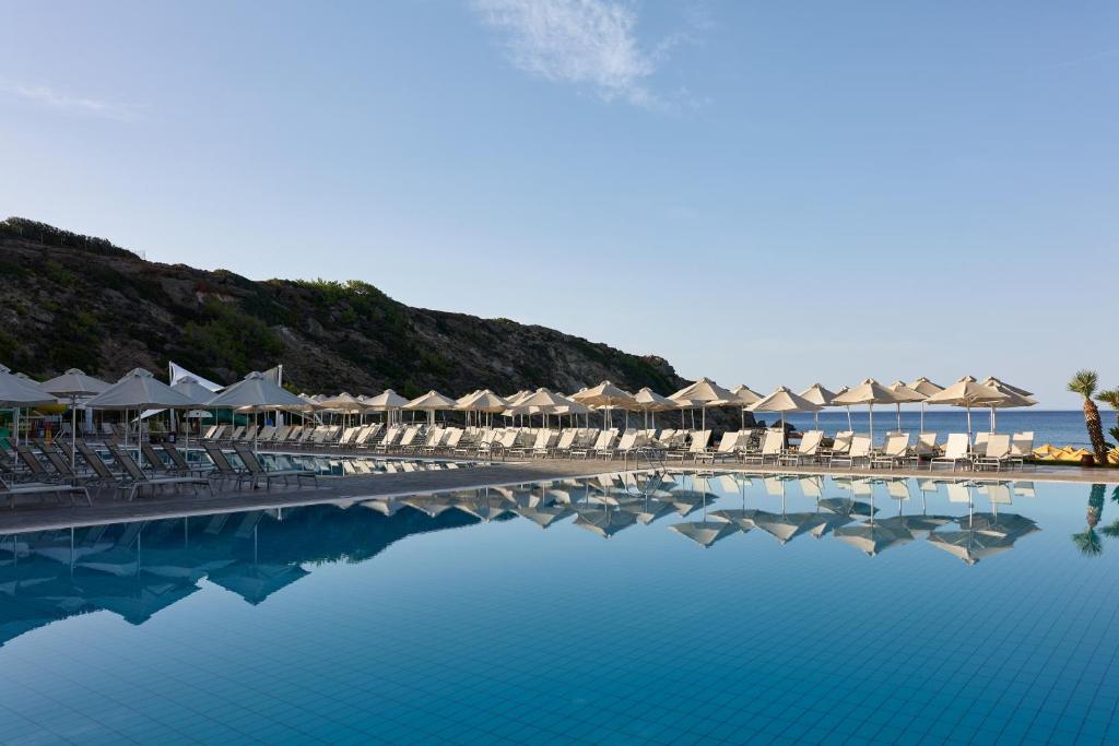 uma piscina com cadeiras e guarda-sóis e o oceano em Atlantica Mikri Poli Crete em Makry Gialos
