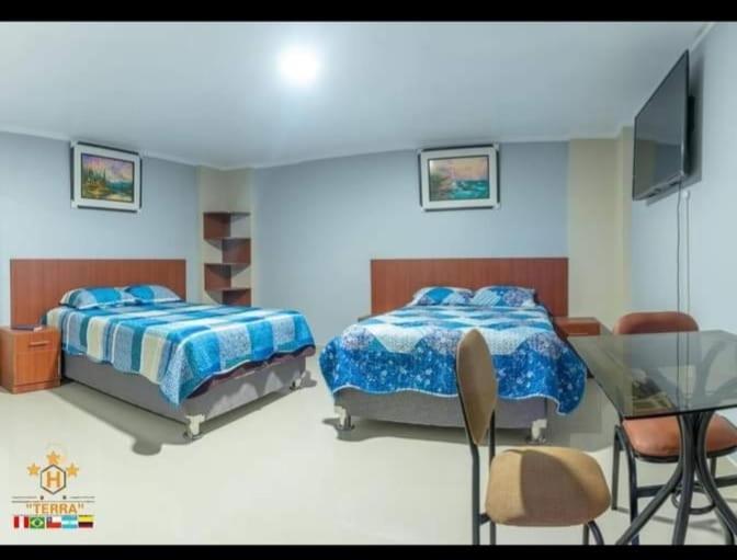 1 dormitorio con 2 camas, mesa y TV en HOTEL TERRA, en Ayacucho