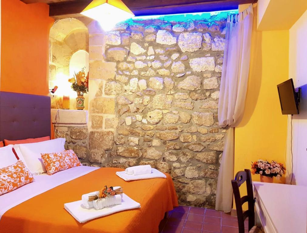 a bedroom with two beds and a stone wall at Tre Archi B&B in Syracuse