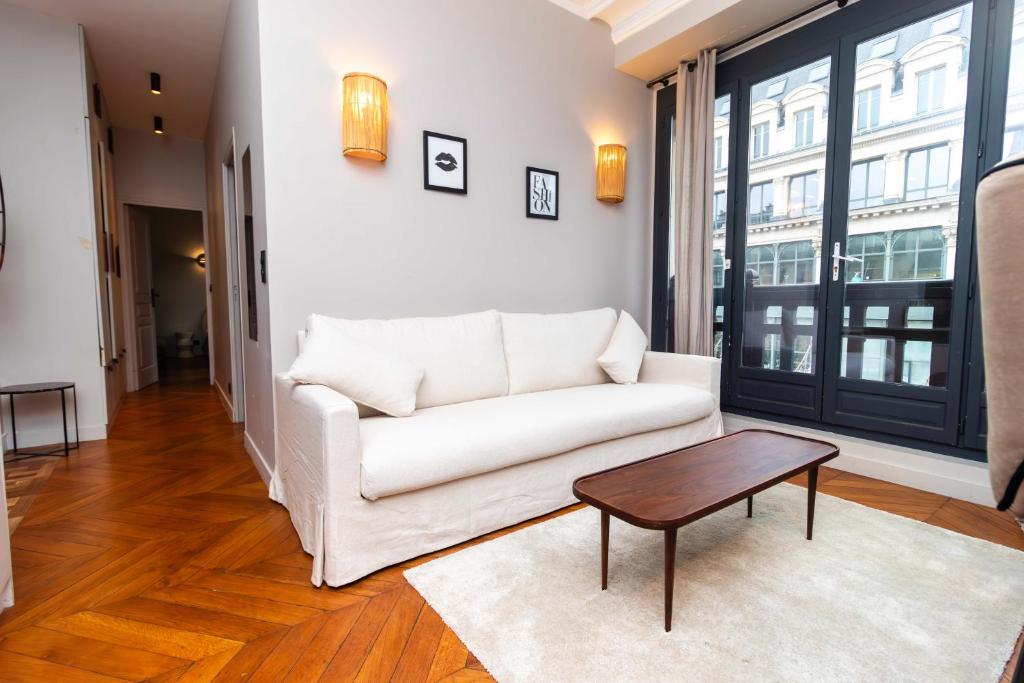 een woonkamer met een witte bank en een tafel bij Apartment Center of Paris by Studio prestige in Parijs