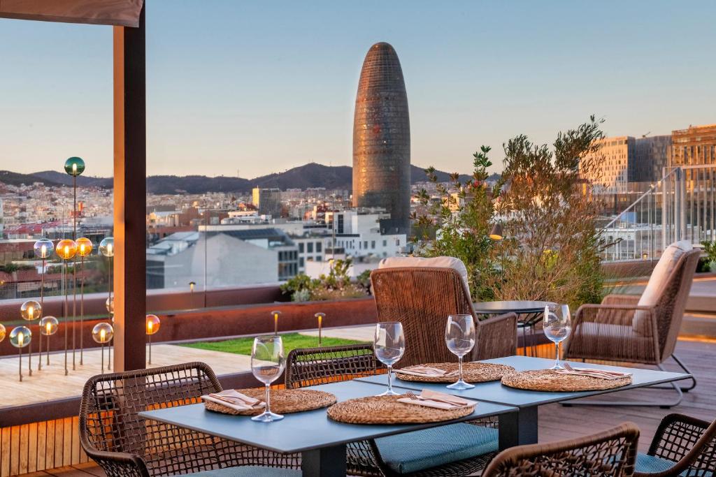 uma mesa com copos de vinho e vista para a cidade em Sallés Hotel Pere IV em Barcelona