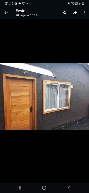 ein Haus mit einer Holztür und zwei Fenstern in der Unterkunft Cabaña cómoda 1 dormitorio in Coihaique