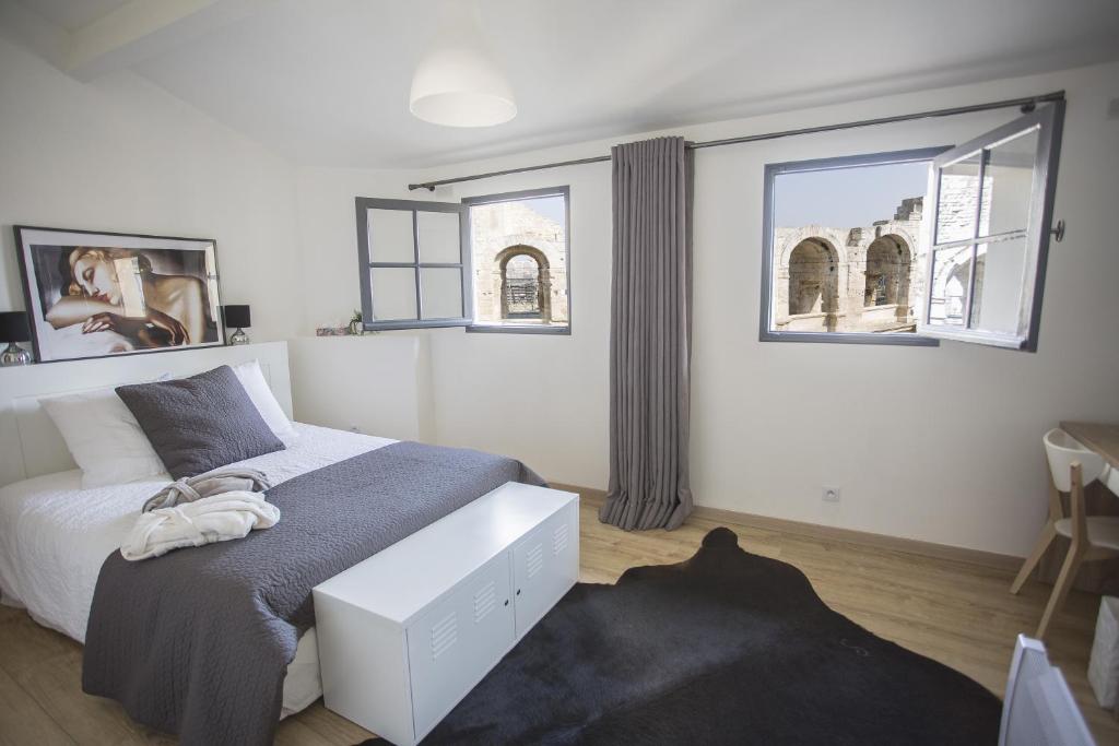 a bedroom with a bed and two windows at Arles Hideaway - Le Duplex des Arènes in Arles